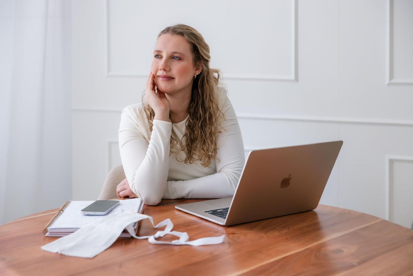 Debra Bekker aan een houten tafel met een laptop en haar advocatenbef, in gedachten
