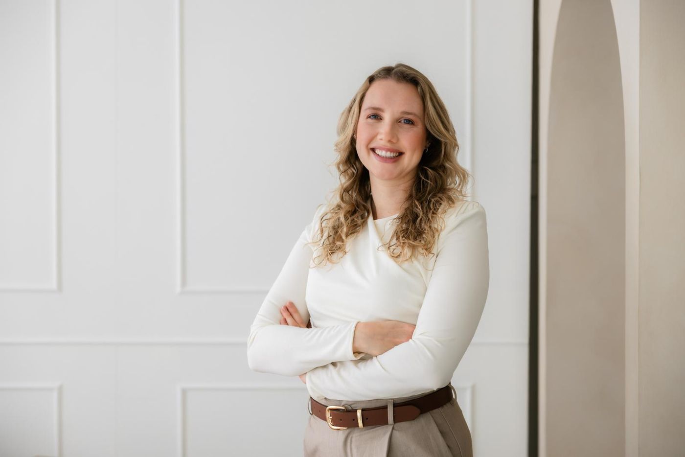 Debra Bekker lacht met de armen over elkaar in een lichte ruimte