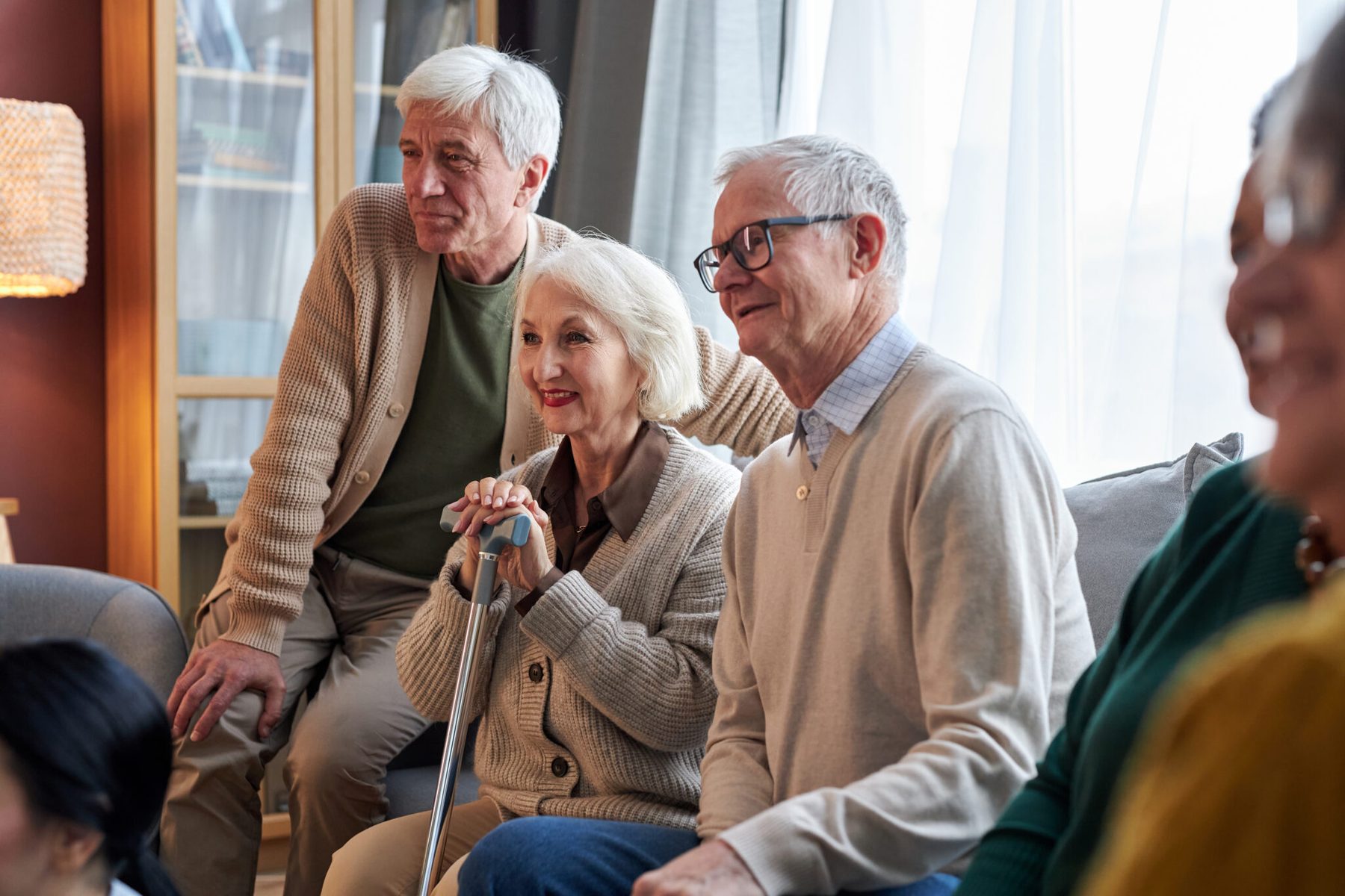 Groep ouderen zit samen op een bank in een woonkamer